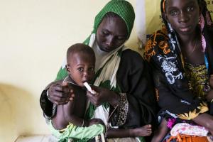 Hassin giving a does of theaputic food to her one year old daughter, Rabia, to test her appetite